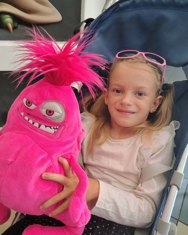Ariana in her pushchair with a big pink soft toy